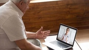 Un homme âgé utilise la téléassistance pour parler à un médecin sur un ordinateur portable.