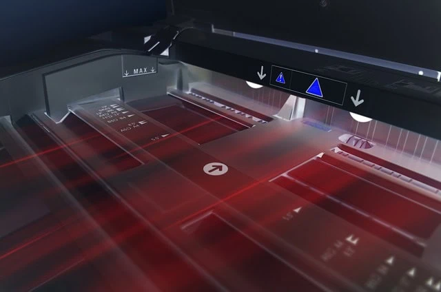 Vue rapprochée d'un scanner à plat en fonctionnement, avec des lumières laser rouges visibles et des marqueurs d'alignement sur la surface de numérisation, idéal pour une numérisation de documents rapide et pas chère.