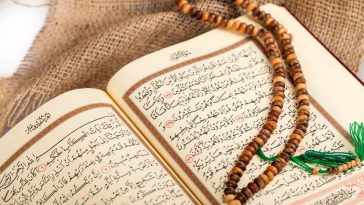 Un Coran ouvert avec un texte arabe est exposé avec un tasbih (chapelet de prière) en bois marron drapé dessus, posé sur un tissu en toile de jute - un cadeau idéal pour l'Aïd el-Fitr.