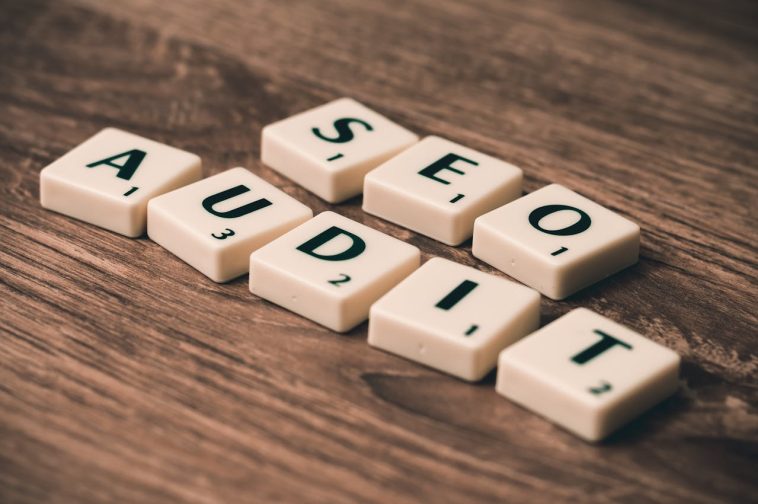 Les tuiles de Scrabble portant l'inscription « AUDIT SEO » sont soigneusement disposées sur une surface en bois, soulignant l'importance de réaliser un audit SEO efficace pour des performances Internet optimales du site.