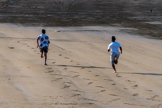 Deux amis, liés par l'amitié, courent le long d'une plage de sable, laissant derrière eux des empreintes de pas.