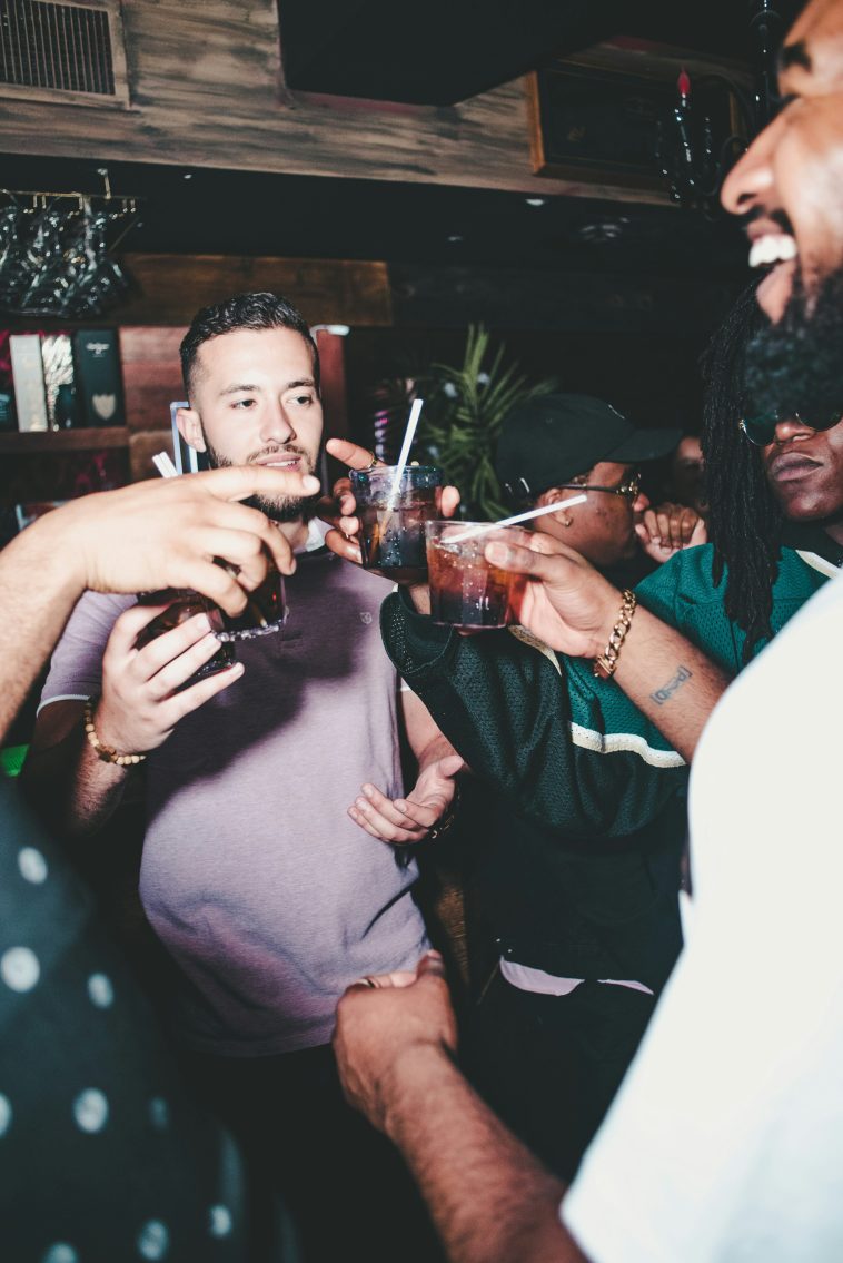 Un groupe de personnes aux yeux éclatants trinquant dans un bar animé, capturant l'essence des soirées parisiennes.